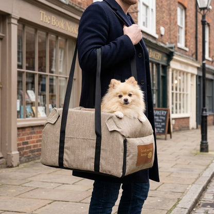 Portable console dog car seat in khaki carried by its webbing straps with a Pomeranian inside