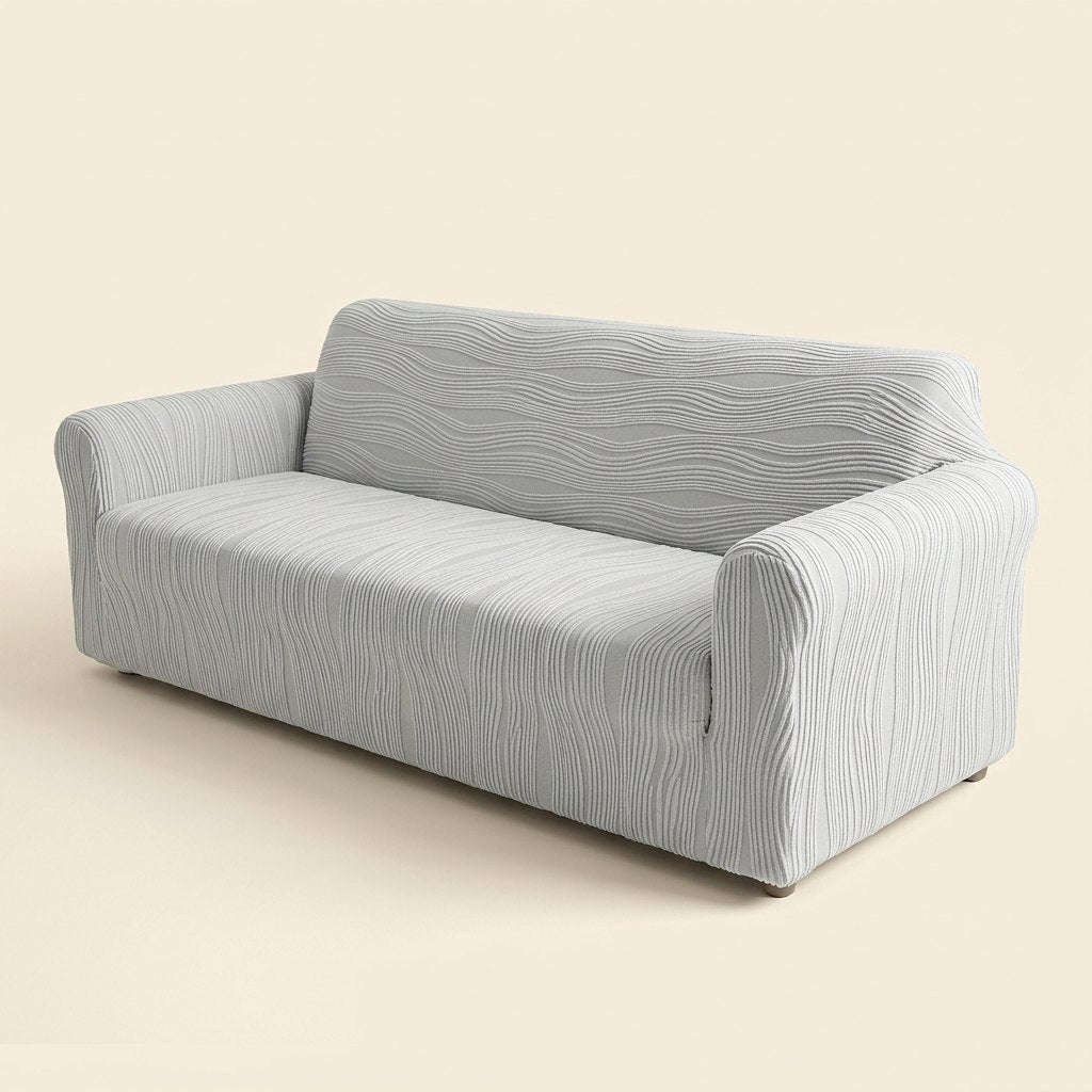 Stretch jacquard sofa cover in light grey fitted on a three-seater sofa, cream studio background